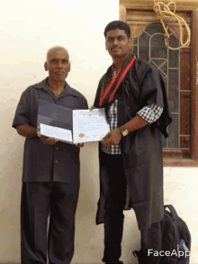 a man in a graduation gown is holding a certificate while standing next to an older man