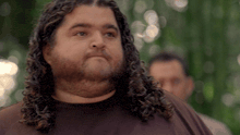 a man with long curly hair and a beard looks to the side