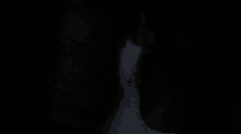 a person is standing in a dark room with a white shirt on