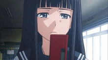 a girl in a school uniform is holding a red cell phone to her mouth .