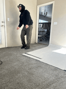 a man in a black hoodie is standing in a living room