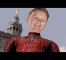 a man in a spiderman suit is smiling in front of a building