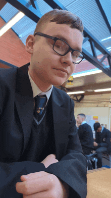 a young man wearing glasses and a suit is sitting at a table