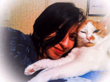 a woman is holding an orange and white cat on a bed