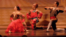 a woman in a red dress is kneeling next to a man in a black and gold outfit