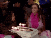 a girl is blowing out candles on a birthday cake with a picture of a woman on it .