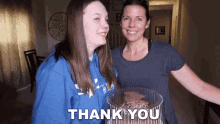 a woman and a girl are standing next to each other and the girl is holding a cake that says thank you on it