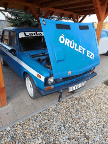 a blue lada car with the hood up and the word orulet on the hood