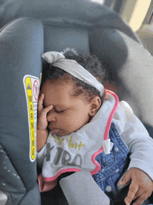 a baby sleeping in a car seat with a warning sticker