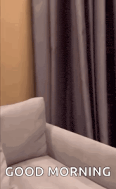 a white couch is sitting in front of a window with the words `` good morning '' on it .