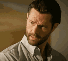 a man with a beard is wearing a white shirt and has his eyes closed