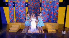 three women are dancing on a stage in front of a wall with suns on it