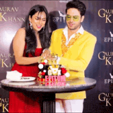 a man in a yellow jacket is cutting a cake with the word epicom on it