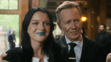 a man and a woman are posing for a picture and the woman has blue lipstick on her lips