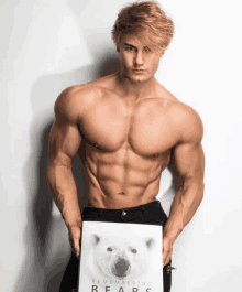 a shirtless man holds up a book titled remembering bears