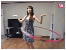 a woman in a blue dress is playing with a pink hula hoop in a living room .