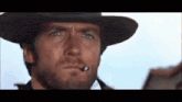 a man with a beard wearing a cowboy hat and smoking a cigarette .