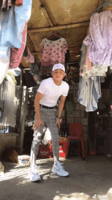 a young man standing in front of clothes hanging on a clothesline with a tiktok watermark on the bottom right