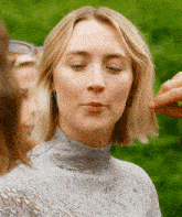 a woman with short blonde hair wearing a turtleneck sweater