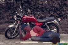 a man is laying on the ground next to a honda motorcycle