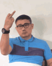 a man wearing glasses and a blue shirt is making a middle finger gesture