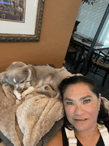 a woman is laying on a couch with a dog sleeping on her lap