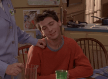 a man in an orange sweater is sitting at a table