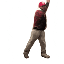 a man wearing a red hat is walking with his hand up