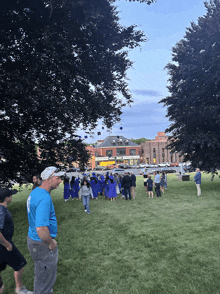 a group of graduates are gathered in a park with a building in the background