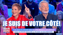 a man and a woman are sitting in front of a crowd and the words je suis de votre cote are on the screen