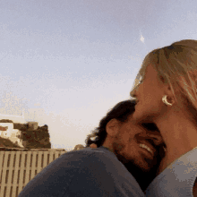 a man and a woman are hugging each other and the woman is wearing gold earrings