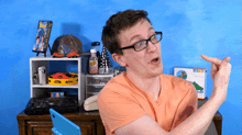 a man wearing glasses and an orange shirt points to a box that says intex on it
