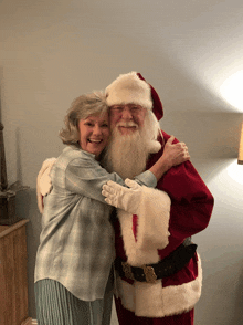 a man dressed as santa claus is hugging a woman