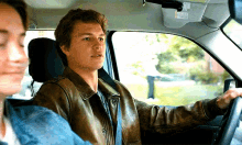 a man in a leather jacket driving a car