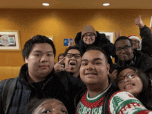 a group of young people posing for a picture with one wearing a sweater that says ' christmas ' on it