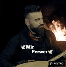 a man with a beard is playing a guitar in front of a fire with the words mir perwer on the bottom