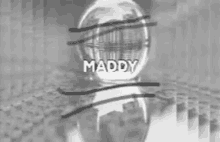 a black and white photo of a snow globe with the word maddy on it .