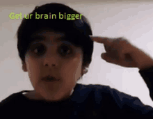 a young boy is pointing his finger at his head with the words get ur brain bigger written above him