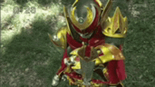 a man in a red and gold armor is holding a sword in his hand .