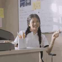 a girl with pigtails is sitting at a desk in front of a whiteboard that says ' chemistry club ' on it