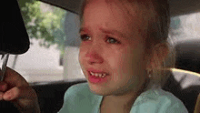 a little girl is crying in a car .