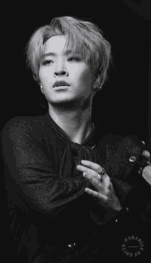 a black and white photo of a young man holding a microphone in a dark room .