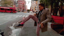 a man in a suit and tie is standing on a sidewalk in front of a red bus that says one way