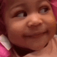 a close up of a baby 's face with a pink hat on