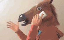 a person wearing a horse head mask is talking on a cell phone .