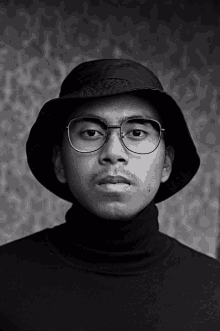 a black and white photo of a man wearing glasses and a bucket hat