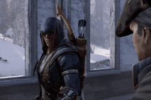 a man in a hooded jacket holds a bow and arrow while standing in front of a window