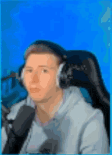 a man wearing headphones is sitting in a chair with a blue background