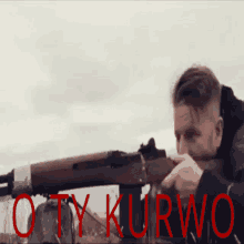 a man is holding a rifle in front of a sign that says " otwurwo "