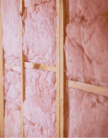 a wall with pink insulation on it and wooden beams